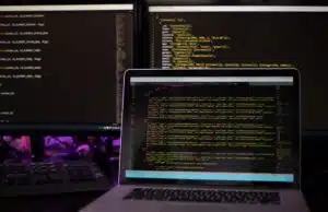 Three computer screens with computer programming code