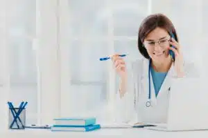 Glad professional doctor concentrated in modern laptop