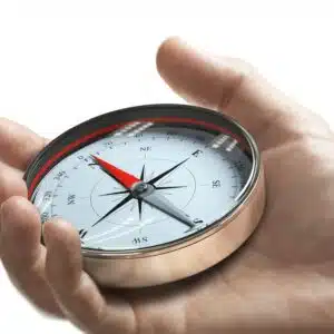 Hand holding a compass over white background. Strategic orientation or direction concept.